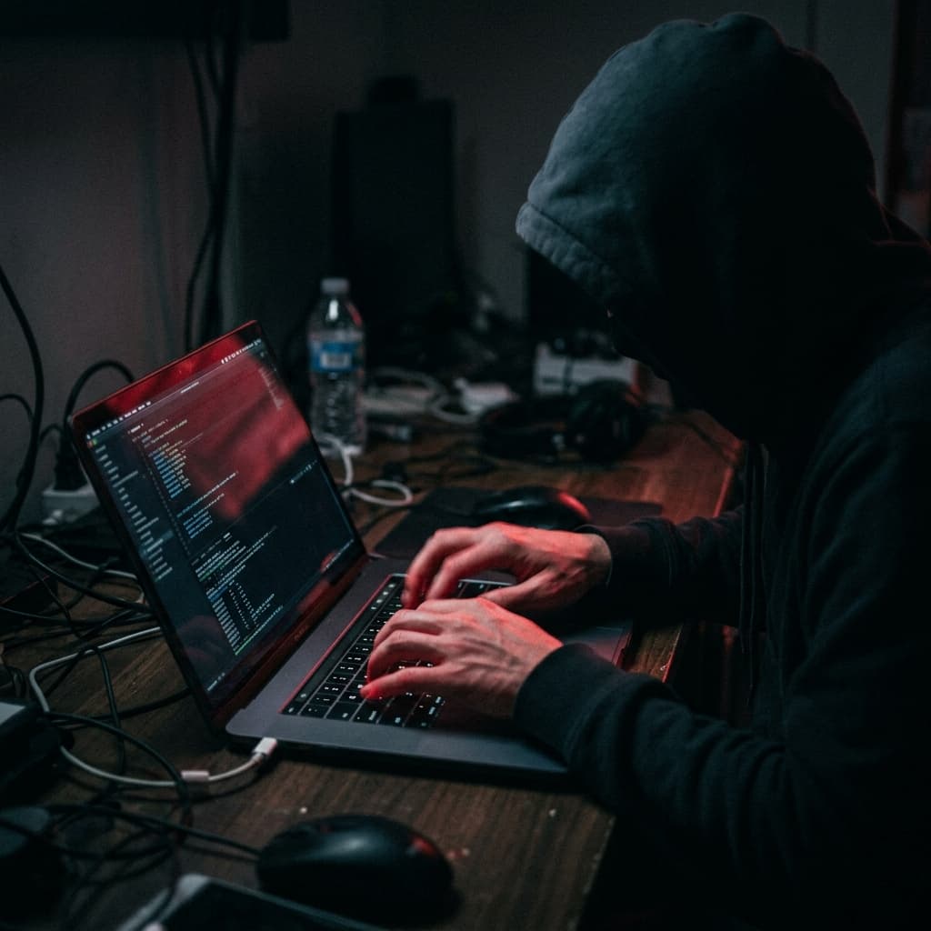 A dark cinematic shot of an anonymous figure aggressively typing on a laptop launching a digital review attack